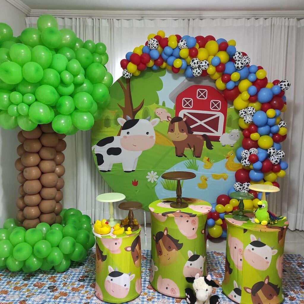 Festa Fazendinha é sucesso entre os temas de aniversário 1 ano. Fundo de bolo com árvore de balões e arco de balões coloridos.